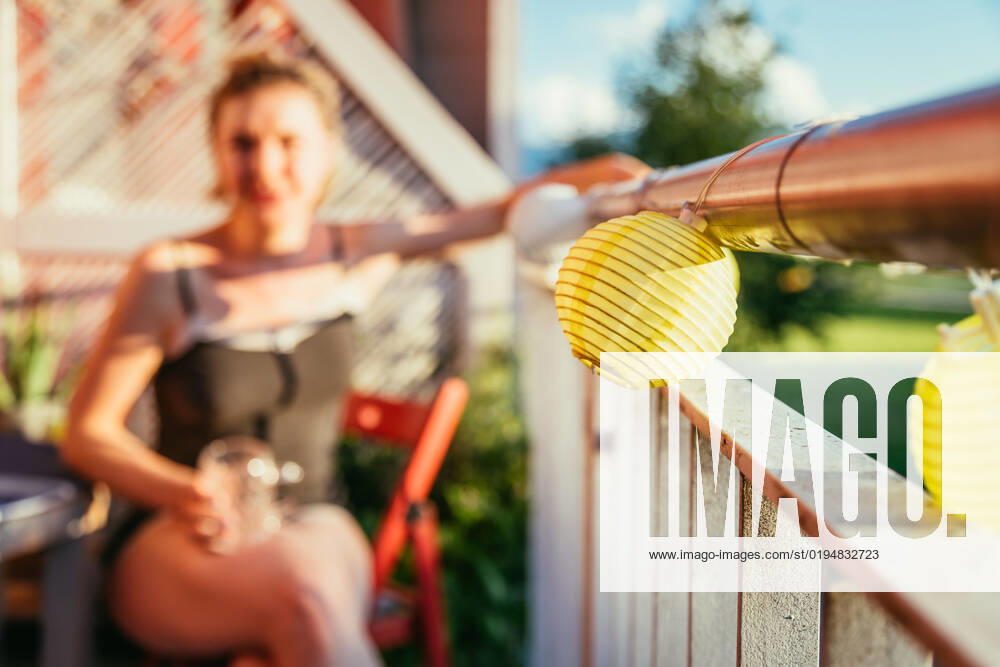 Summer feeling on the balcony: Close up of lampions, smiling girl in the blurry background Close up of summer lampions on a balcony, girl in the blurry background. Leisure time in the summer holidays