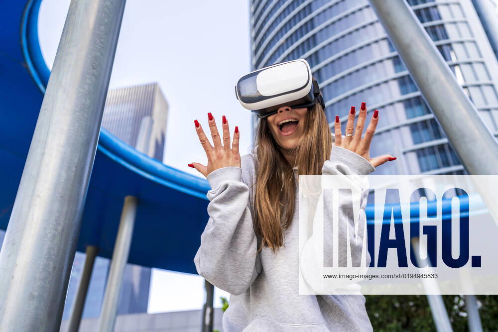 Excited woman wearing virtual reality simulator in front of building model released, Symbolfoto, DLTSF03215