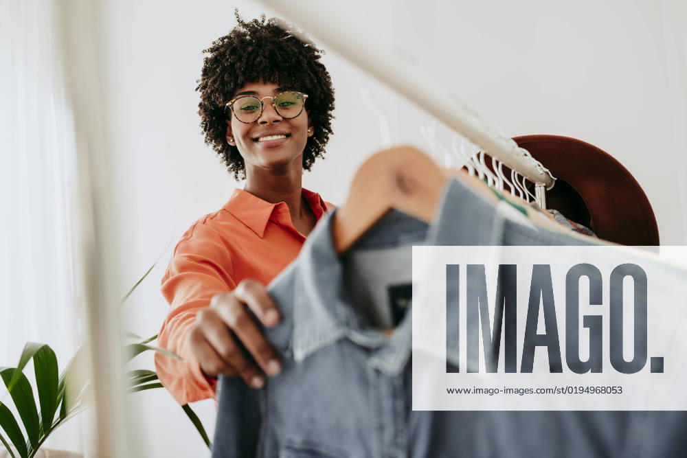 Smiling businesswoman wearing eyeglasses holding clothes at home office model released, Symbolfoto property released, EBBF06863