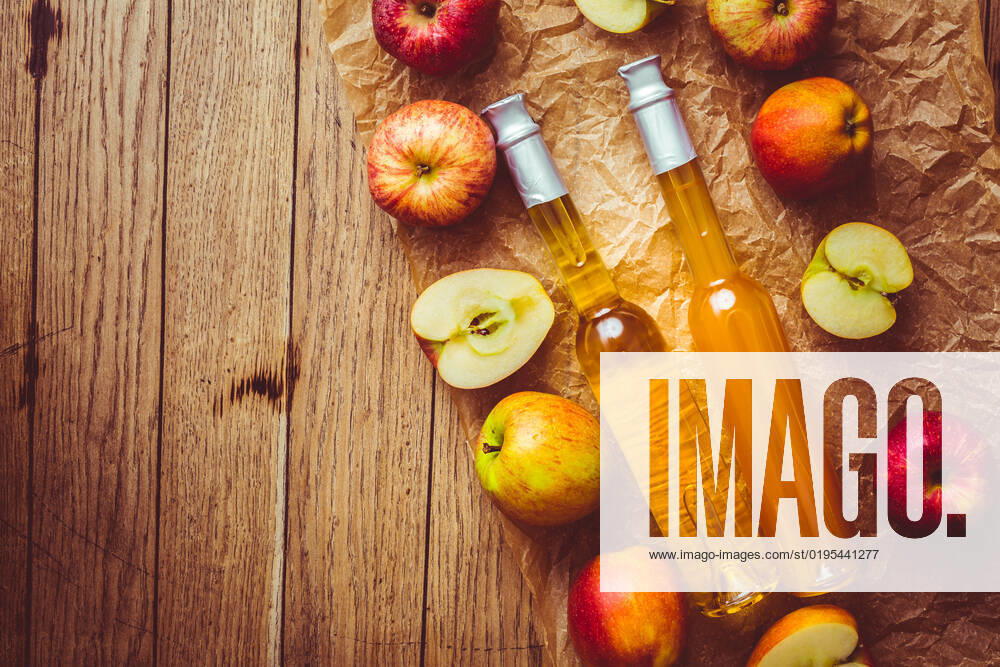 Apple juice with apple vinegar in bottles and fresh apples on wooden background Apple juice with apple vinegar in bottles and fresh apples on wooden background