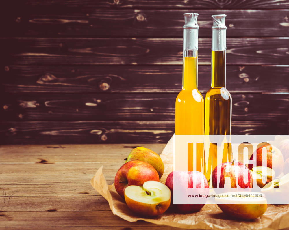 Apple juice with apple vinegar in bottles and fresh apples on wooden background Apple juice with apple vinegar in bottles and fresh apples on wooden background
