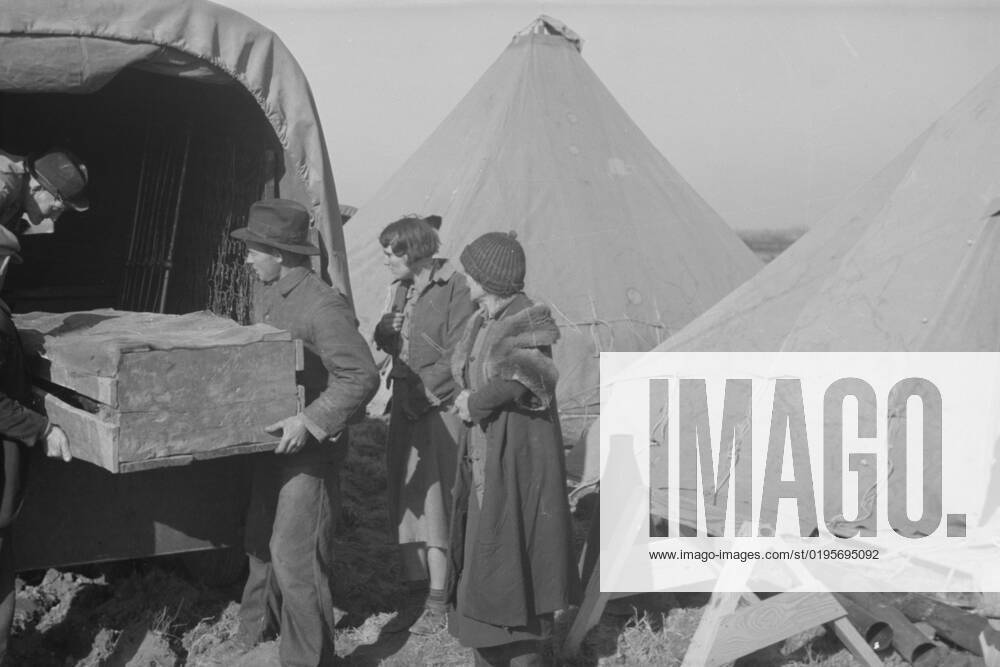 Unloading household goods of a family of white flood refugees in camp, Forrest City, Arkansas, 1937. Creator: Walker Evans.