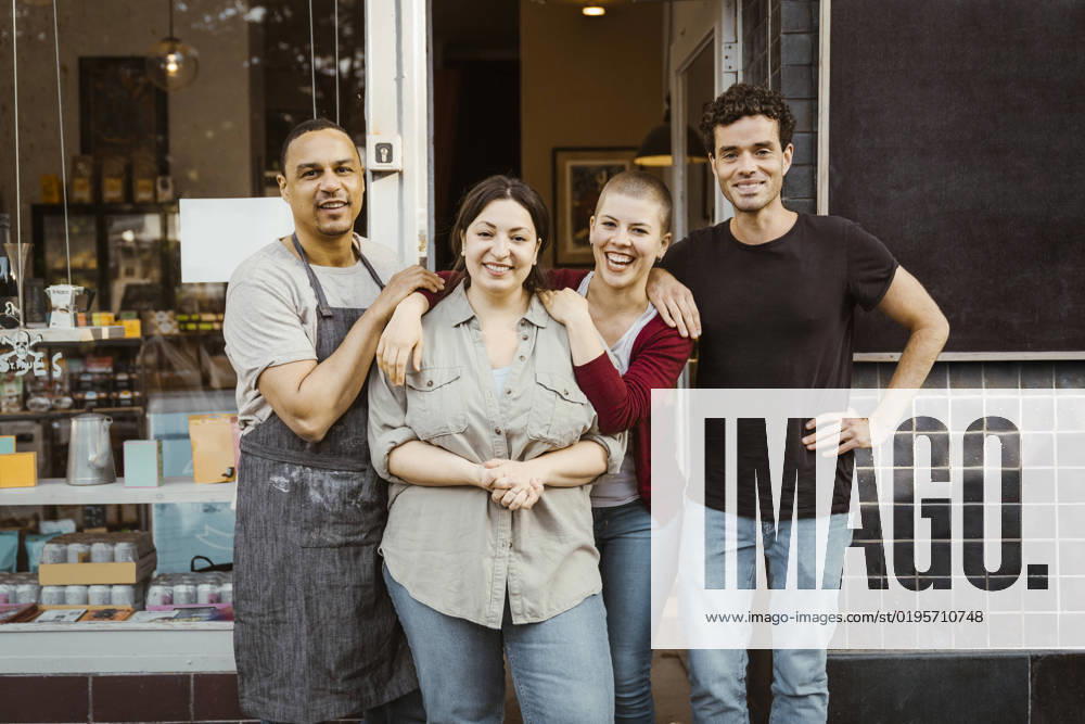 Portrait of happy multiracial male and female business owners standing outside store