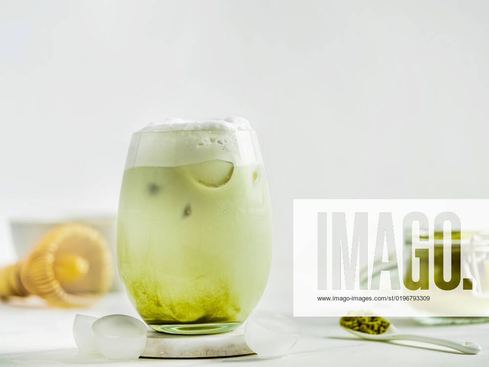 Iced Matcha Latte Tea with whipped cream Iced Matcha Latte Tea with whipped cream in tumbler glass and ingredients on white marble background. Copy space for txt or design