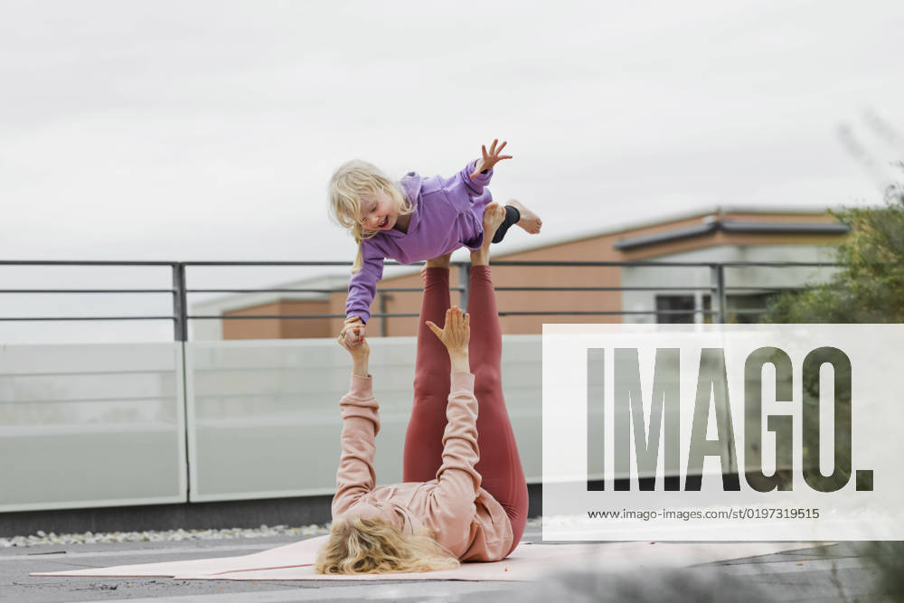 IMAGO Creative, Urban Lifestyle Mother balancing girl on legs lying down at rooftop model released, Symbolfoto, München Bayern Deutschland Gertrud-Grunow-Strasse AANF00412