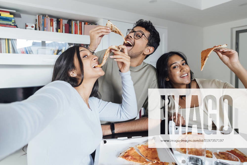 IMAGO Creative, Lifestyle, Leben in einer Wohngemeinschaft, WG Happy young woman taking selfie with woman and man having pizza at home model released, Symbolfoto property released, MEUF08632