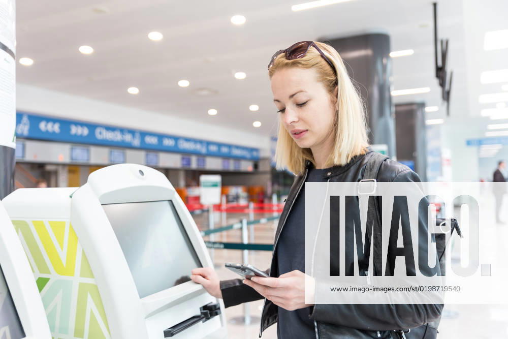 Casual caucasian woman using smart phone application and check-in machine at the airport getting the boarding pass. Casual caucasian woman using smart phone application and check-in machine at the airport getting the boarding pass. Modern technology on airport.
