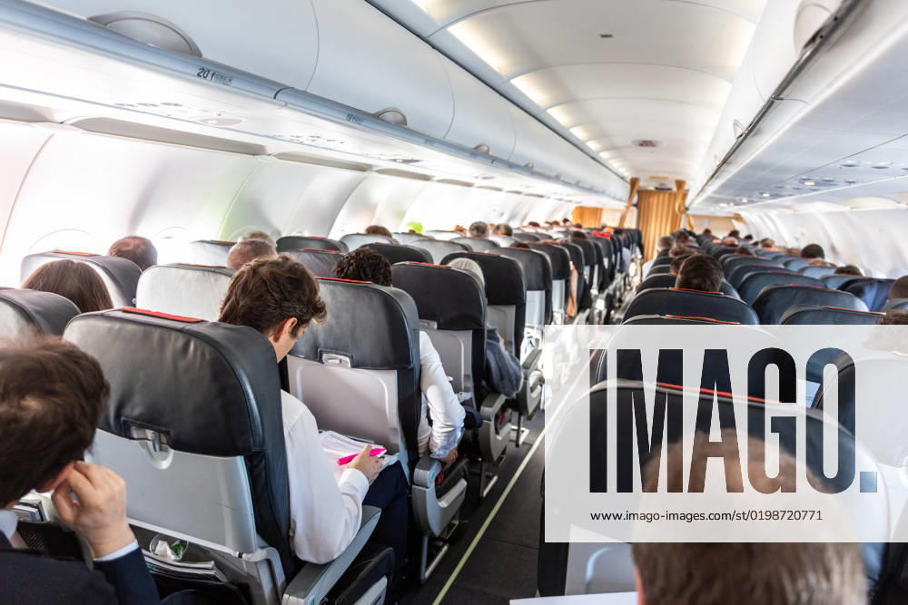 Interior of commercial airplane with passengers on their seats during flight. Interior of commercial airplane with unrecognizable passengers on their seats during flight.