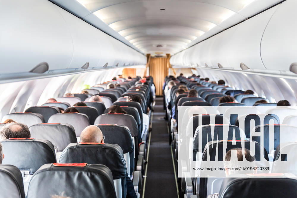 Interior of commercial airplane with passengers on their seats during flight. Interior of commercial airplane with unrecognizable passengers on their seats during flight shot from the rear of airplane.