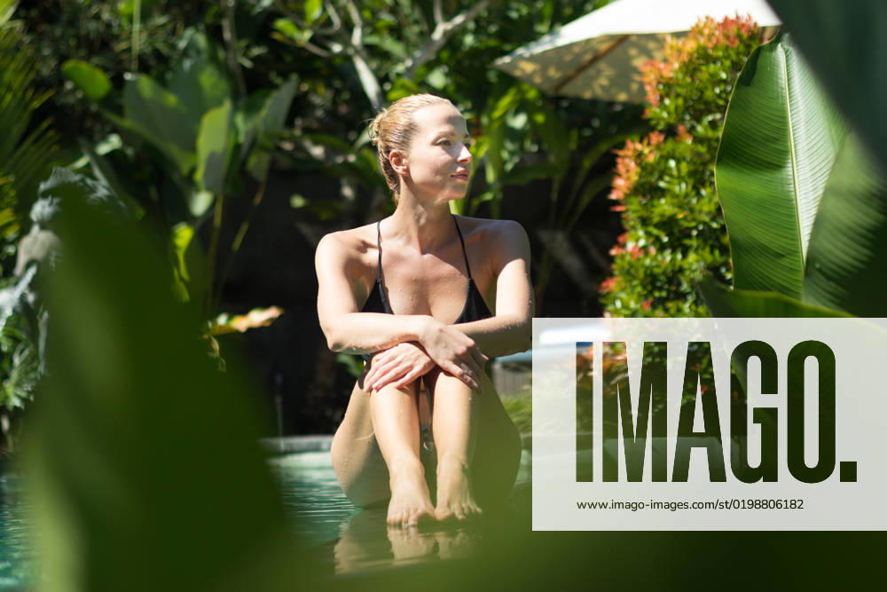 Sensual young woman relaxing in outdoor spa infinity swimming pool surrounded with lush tropical greenery of Ubud, Bali. Sensual young woman relaxing in outdoor spa infinity swimming pool surrounded with lush tropical greenery of Ubud, Bali. Wellness, natural beauty and body care concept.