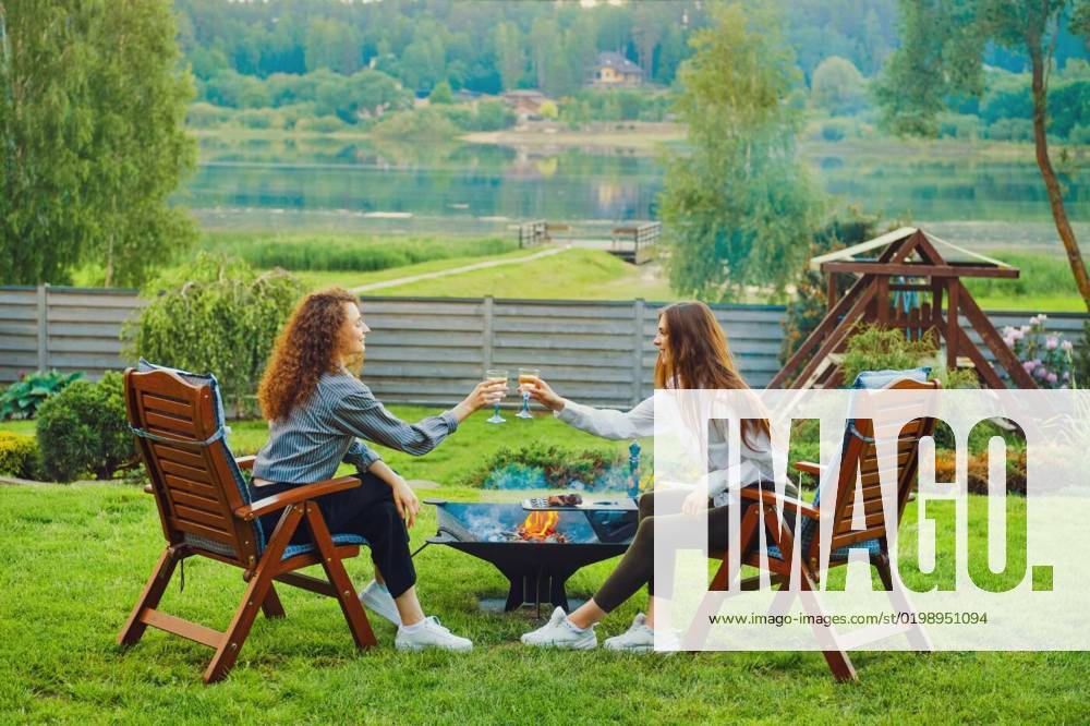 Two friends clinking glasses in backyard, Two women clinking wine glasses in backyard, Two women clinking wine glasses in backyard model released, Symbolfoto , 28.11.2022,
