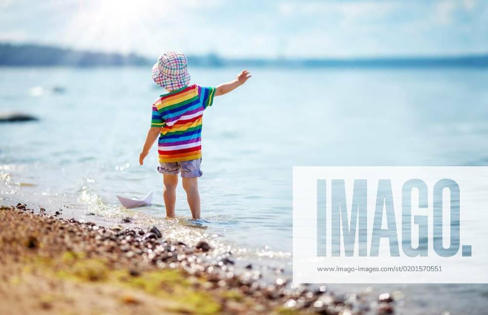 IMAGO Creative, Jahreszeit Sommer, Hitze Cute boy playing with paper boat on the seashore., Cute boy playing with paper boat on the seashore. Concept of cruise and family vacation., Cute boy playing with paper boat on the seashore. Concept of cruise and family vacation. model released, Symbolfoto , 19.01.2023,