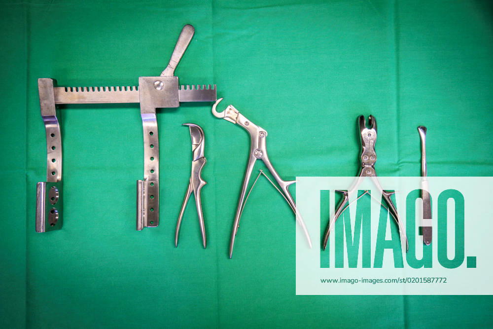 Some surgical rib instruments lie on a green surgical cloth