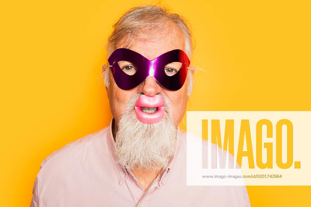 IMAGO Creative, Gesellschaft, Fasching Positive bearded aged male in pink shirt wearing carnival mask and funny lips looking at camera on yellow background, Model released HodeiUnzueta_ID12634_384197_009