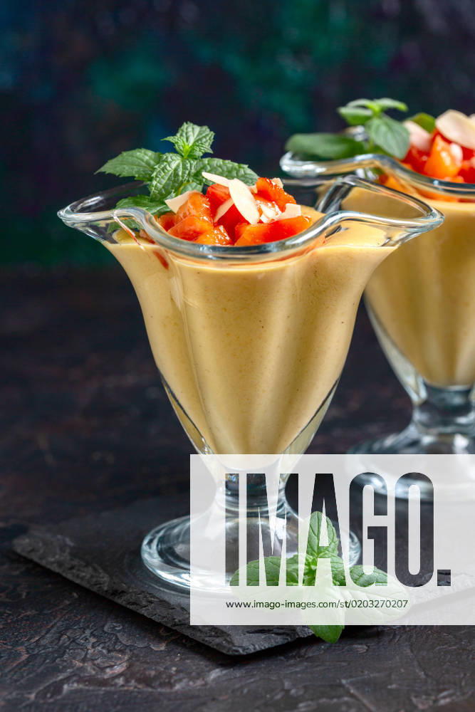 Dessert with peach slices and mint. Delicate dessert of milk, cream and fresh peaches in dessert glasses, served with slices of fresh mint and peach on a slate stand, selective focus. Copy space.