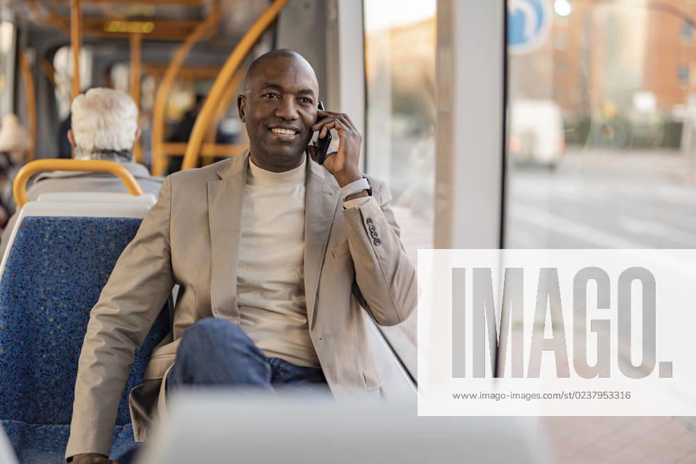 Smiling mature commuter talking on smart phone in cable car model released, Symbolfoto, JCCMF09270