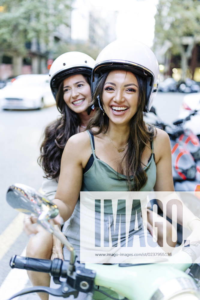 Happy woman with friend sitting on electric scooter model released, Symbolfoto, JJF00213