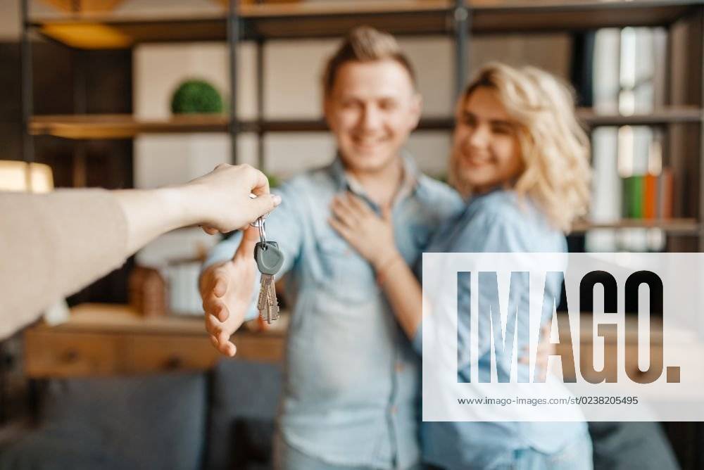 Newly married love couple receive as a gift the keys to the apartment. Happy lifestyle, beautiful relationship. Smiling husband and wife takes a present