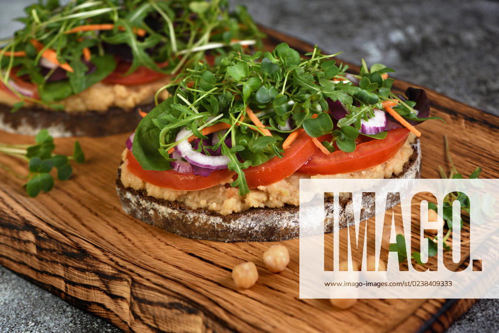 IMAGO Creative, Food, Hummus Vegetarian sandwich with microgreen Sandwich toasted rustic bread with chickpea hummus, tomato slices, mix of lettuce and microgreens. Vegetarian breakfast.