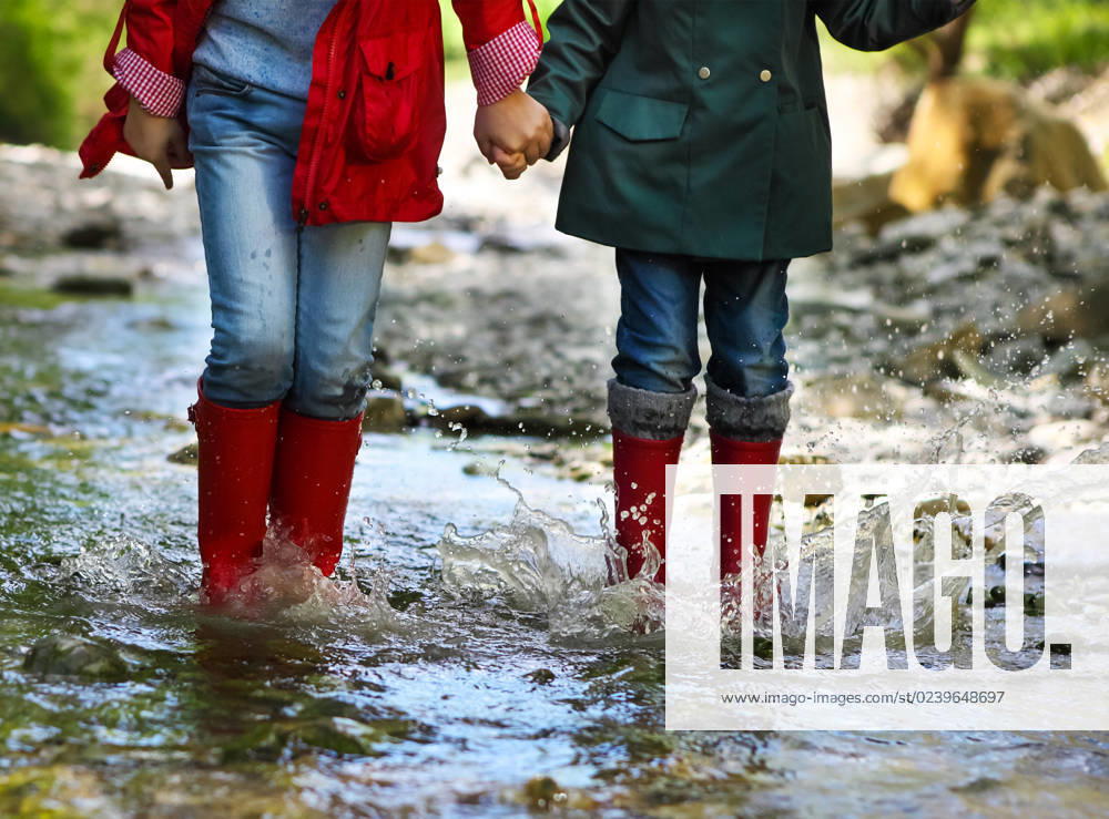 Child wearing rain boots jumping. Close up Children wearing rain boots jumping into a mountain river. Close up ,model released, Symbolfoto