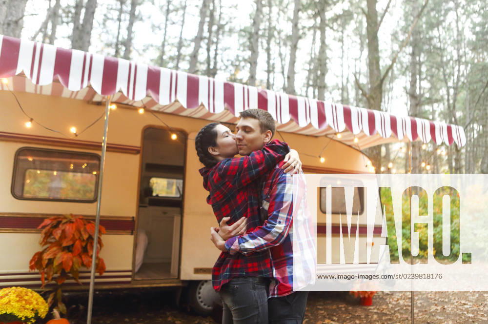 Portrait of romantic couple smiling while holding hands near house on wheels outdoors Portrait of romantic couple man and woman smiling while hugging near house on wheels outdoors ,model released, Symbolfoto