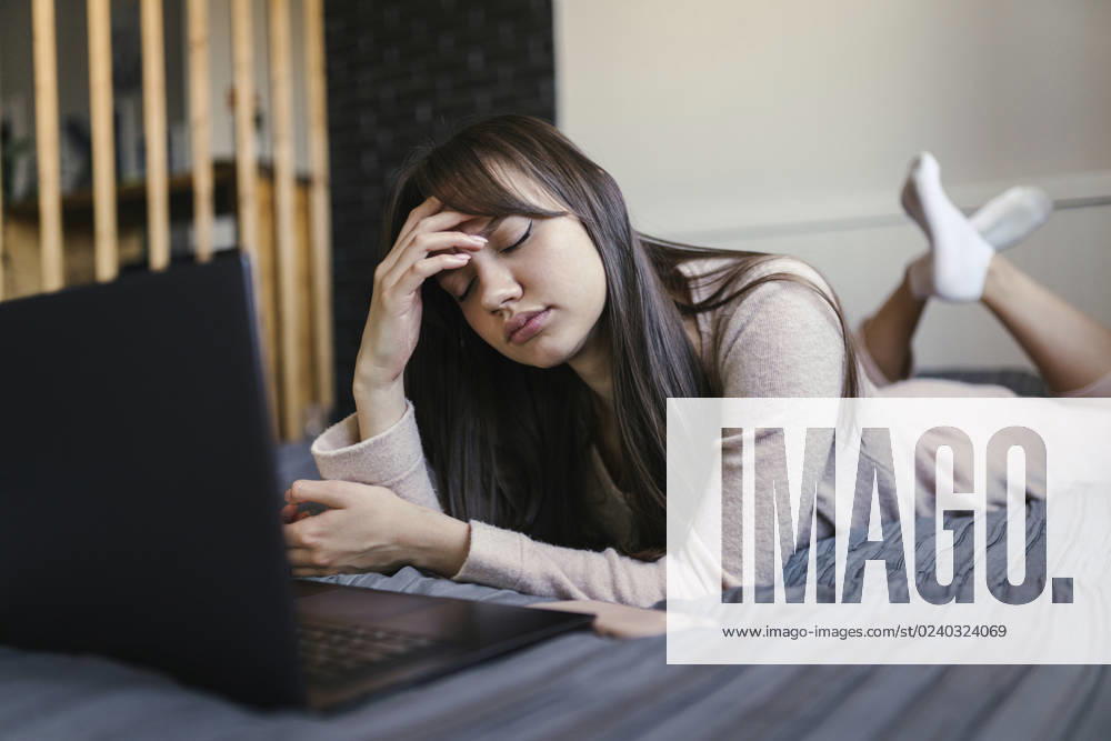 Tired young woman with eyes closed lying on bed at home model released, Symbolfoto property released, ANNF00044