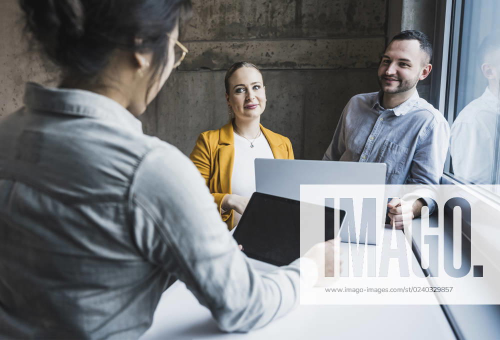 Smiling colleagues looking at businesswoman using tablet PC in meeting at office model released, Symbolfoto property released, UUF28471