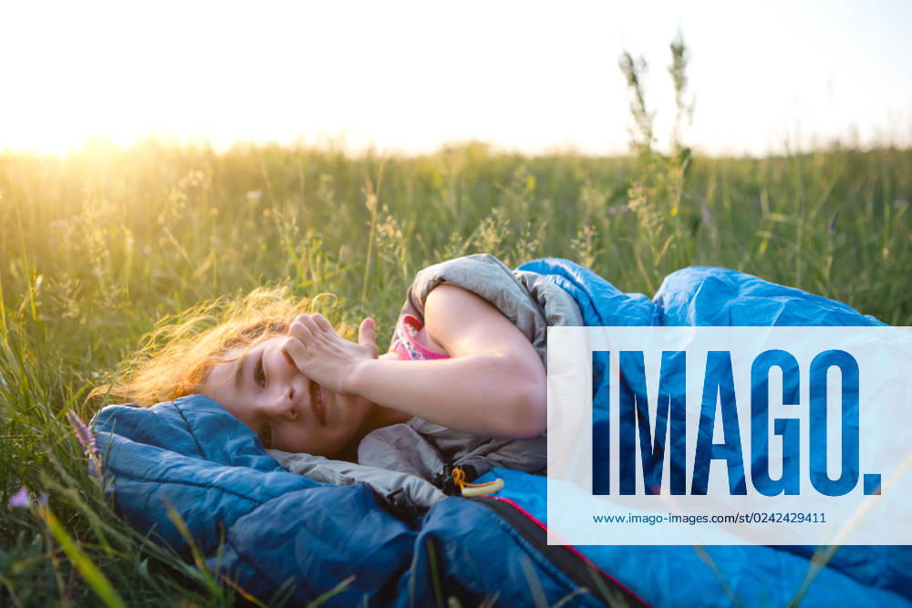 The girl is dissatisfied with scratching mosquito bites, child sleeps in a sleeping bag on the grass in a camping trip. Eco-friendly outdoor recreation, summer time. Sleep disturbance, repellent. The girl is dissatisfied with scratching mosquito bites, child sleeps in a sleeping bag on the grass in a camping trip. Eco-friendly outdoor recreation, summer time. Sleep disturbance, repellent. ,model released, Symbolfoto