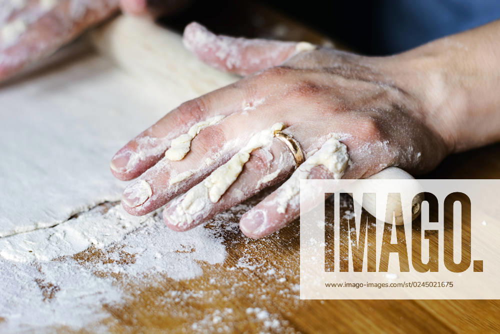 Female hands using a rolling pin to pave a dough over a wooden board dirty with flour. female hands using a rolling pin to pave a dough over a wooden board dirty with flour. Preparation of flour-based food such as bread or pizza