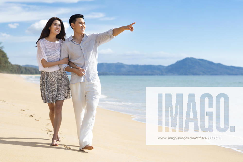 Happy young Chinese couple walking on beach Beijing China