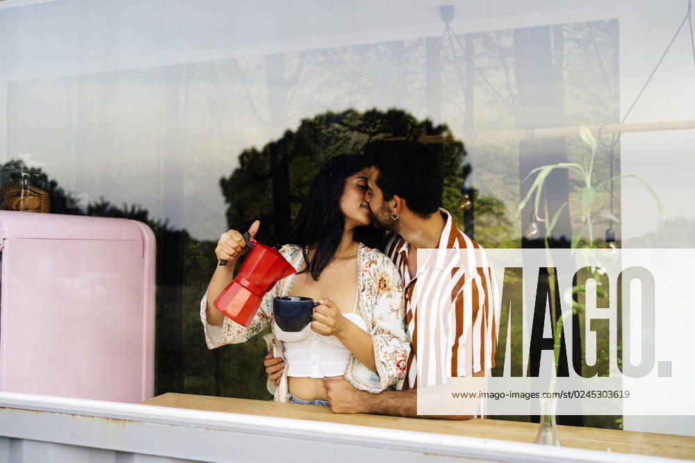 Man kissing girlfriend pouring coffee in cup at home model released, Symbolfoto property released, JJF00468