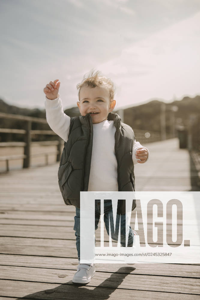 Happy cute son wearing padded jacket running at jetty on sunny day model released, Symbolfoto, MTBF01266