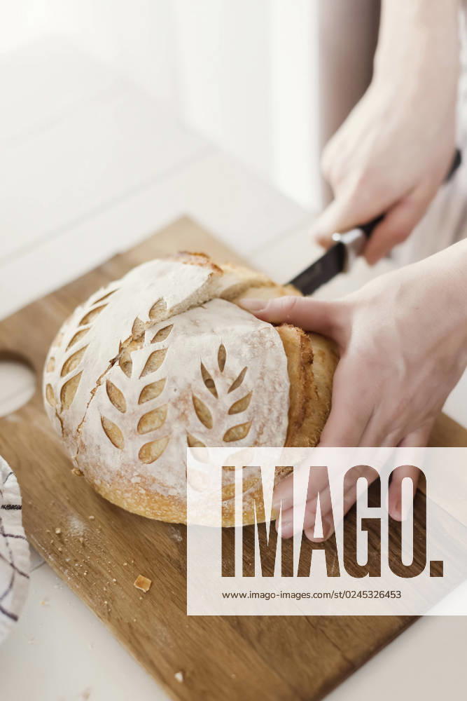 Hands of woman cutting loaf of bread on board model released, Symbolfoto property released, ONAF00486