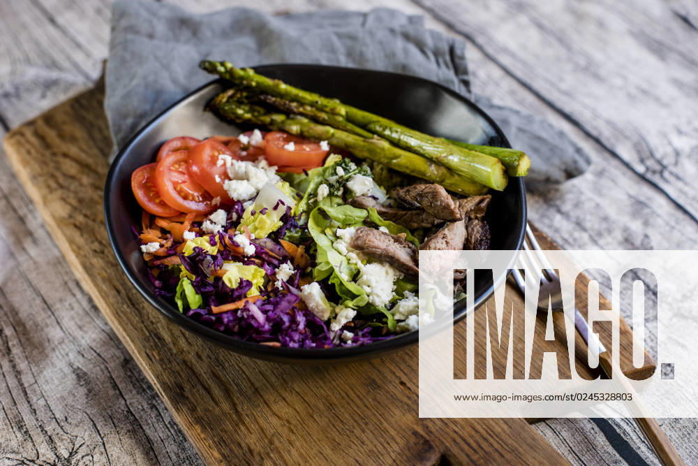 Bowl of salad with steak, asparagus, tomatoes, shredded red cabbage, lettuce and feta cheese, SBDF04609