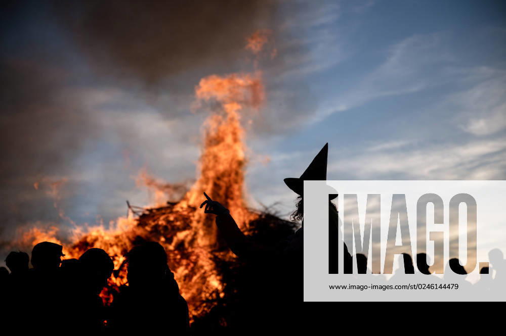 Weimarer Land - Bergern: Ein Mädchen als Hexe verkleidet mit einem Hexenhut zeichnet sich als Silhouette vor einem traditionellen Feuer zur Walpurgisnacht ab.