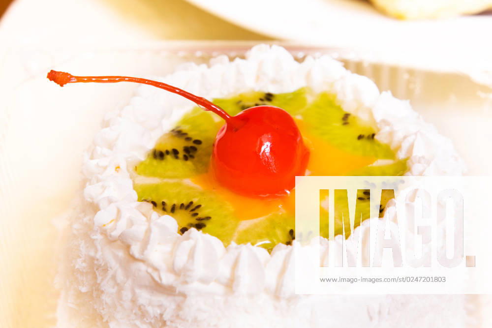 Close-up photo of fancy cake with kiwi and cherry