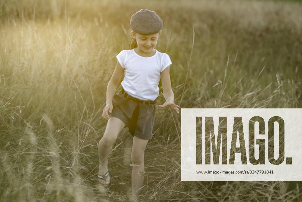 IMAGO Creative: Sommer, Abendspaziergang Mädchen mit Kappe, 8 Jahre, bei Sonneuntergang in der Wiese