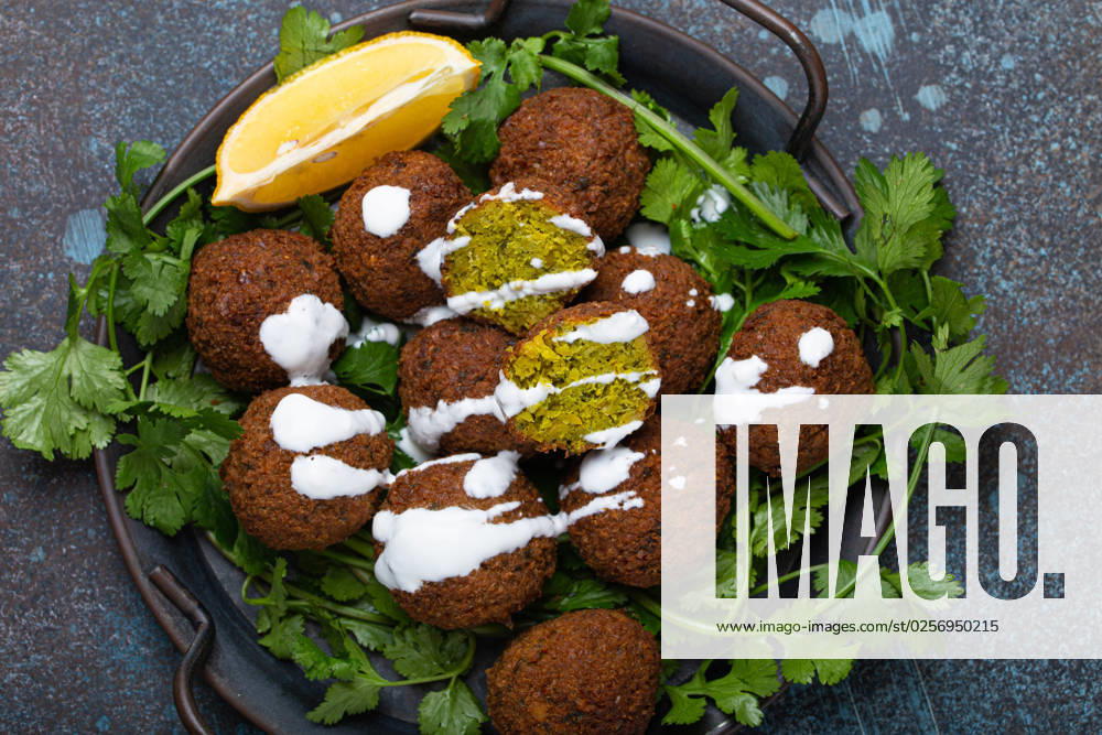 Plate of fried falafel balls served with fresh green cilantro and lemon, top view on rustic concrete background. Traditional vegan dish of Middle Eastern cuisine Plate of fried falafel balls served with fresh green cilantro and lemon top view on rustic concrete background. Traditional vegan dish of Middle Eastern cuisine