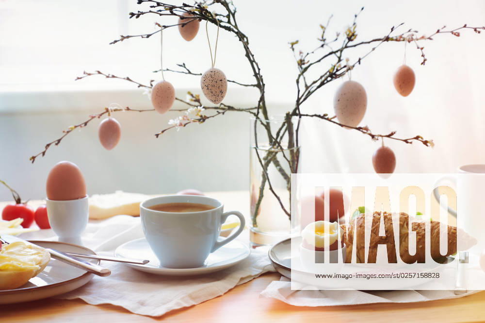 Easter breakfast in the morning sun with coffee and croissant on a table at the window, decoration from natural eggs hanging on spring branches, copy space, selected soft focus Easter breakfast in the morning sun with coffee and croissant on a table at the window, decoration from natural eggs hanging on spring branches, copy space, selected soft focus, narrow depth of field