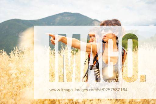 IMAGO Creative: Sommer, In den Bergen A Caucasian woman showing something with her finger carrying her son on the back in a wheat field *** einer kaukasisch Frau zeigend etwas mit her finger tragend her Sohn am der Rücken ÊIn einer Weizen Feld 7330887 ,model released, Symbolfoto RECORD DATE NOT STATED