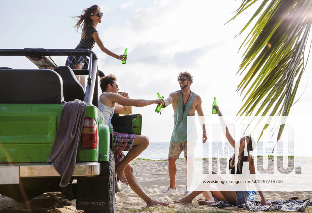 Happy friends toasting drink bottles with off-road vehicle at beach model released, Symbolfoto, IKF00274