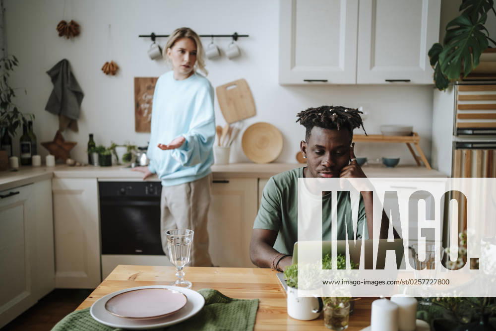 Woman arguing with man sitting with laptop in kitchen at home model released, Symbolfoto property released, MDOF01098