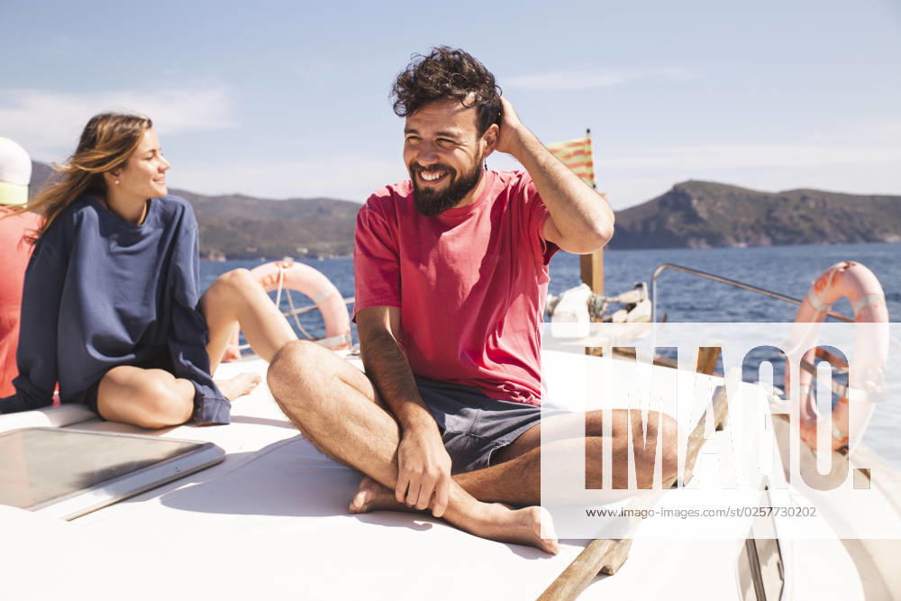 Smiling man sitting cross-legged by woman on yacht at vacation model released, Symbolfoto, PCLF00478