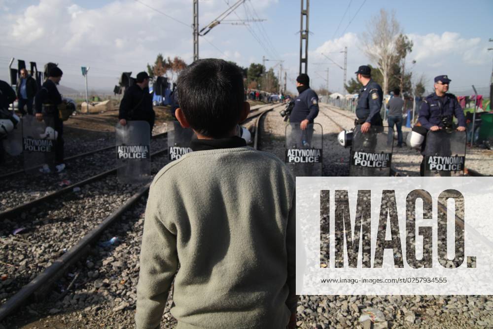 Flüchtlingsjunge in Griechenland Flüchtlinge auf der Balkanroute an der Grenze zwischen Griechenland und Mazedonien ( griechisch-mazedonische Grenze ) beim Flüchtlingslager Idomeni am 01.03.2016: Ein kleiner Junge ( Kind ) steht vor griechischen Polizisten ( Polizei )
