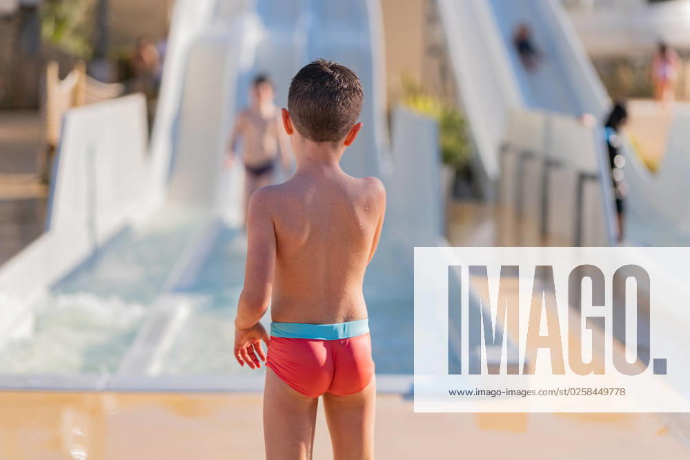 MR_ID14021_13417_EtxahunUnzueta.jpg Back view of unrecognizable child in a red swimsuit near the exit of a slide while standing against a blurry kid at a water park, Model released HodeiUnzueta_ID14021_423000_004