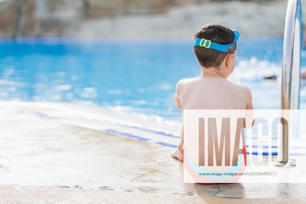 MR_ID14021_13417_EtxahunUnzueta.jpg Back view of unrecognizable kid with swimming goggles on his head sitting with his hands together on folded legs as he stares into the pool, Model released HodeiUnzueta_ID14021_423070_035