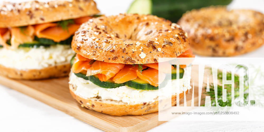 Bagel Brötchen Sandwich zum Frühstück belegt mit Lachs Fisch auf einem Brett Panorama in Stuttgart, Deutschland Stuttgart, Deutschland - 15. März 2023: Bagel Brötchen Sandwich zum Frühstück belegt mit Lachs Fisch auf einem Brett Panorama in Stuttgart, Deutschland.