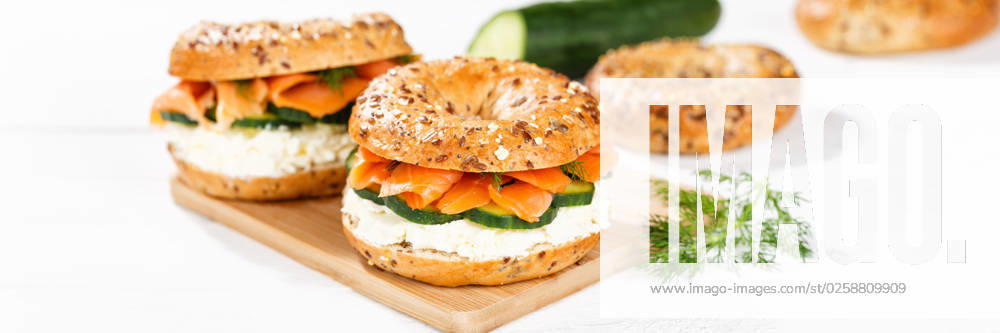 Bagel Brötchen Sandwich zum Frühstück belegt mit Lachs Fisch auf einem Brett Panorama in Stuttgart, Deutschland Stuttgart, Deutschland - 15. März 2023: Bagel Brötchen Sandwich zum Frühstück belegt mit Lachs Fisch auf einem Brett Panorama in Stuttgart, Deutschland.