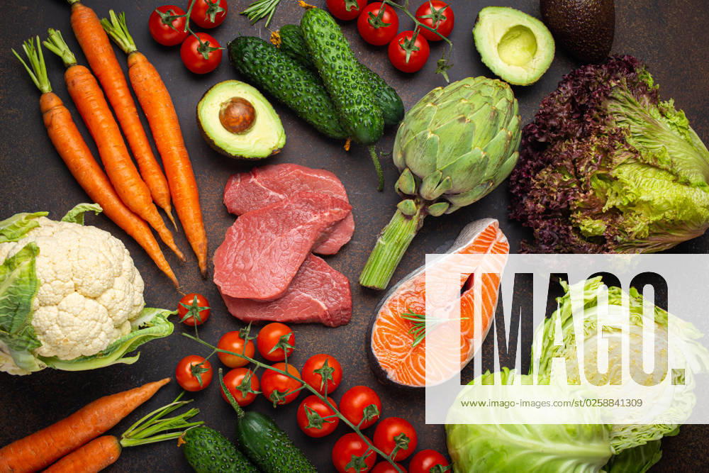 Assorted food raw products: vegetables, beef meat, fish salmon fillet on dark rustic brown stone table top view. Healthy food background, ingredients with vitamins concept, diet and nutrition Assorted food raw products: vegetables, beef meat steak, fish salmon fillet on dark rustic brown stone table top view. Healthy food background, ingredients with vitamins concept, diet and nutrition