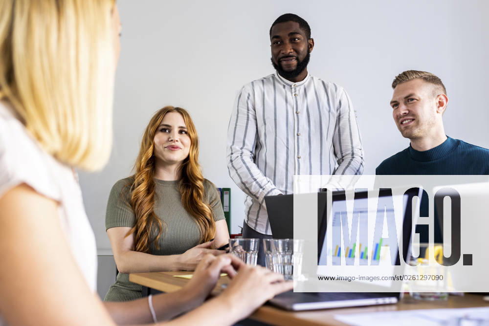 Smiling colleagues looking at businesswoman with laptop in office model released, Symbolfoto property released, WPEF06648